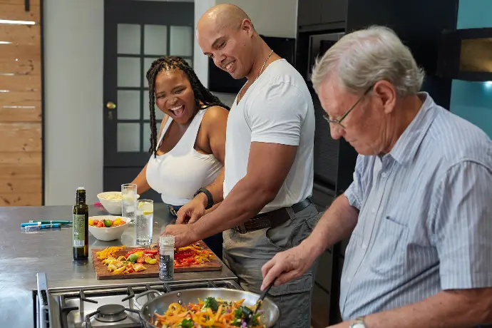 a group of people standing around a kitchen preparing food