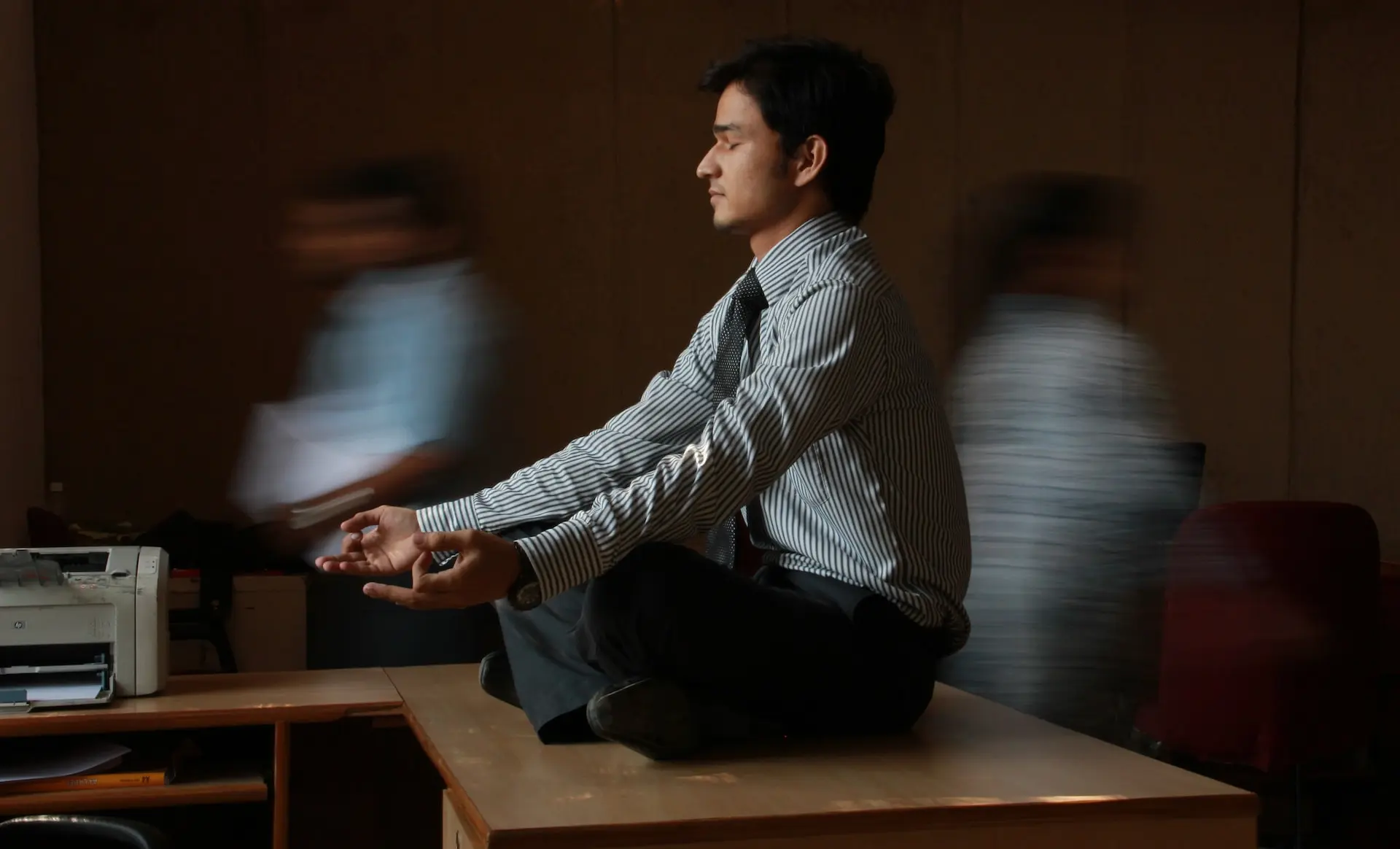 man in white and blue pinstripe dress shirt sitting on brown wooden table